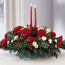 Share the joy this season with a festive fresh arrangement of red carnations and white Gerberas,  Two red taper candles add seasonal charm to this centerpiece. (Please Note That We Reserve The Right To Substitute Any Product With A Suitable Product Of Equal Value In Case Of Non-Availability Of A Certain Product)